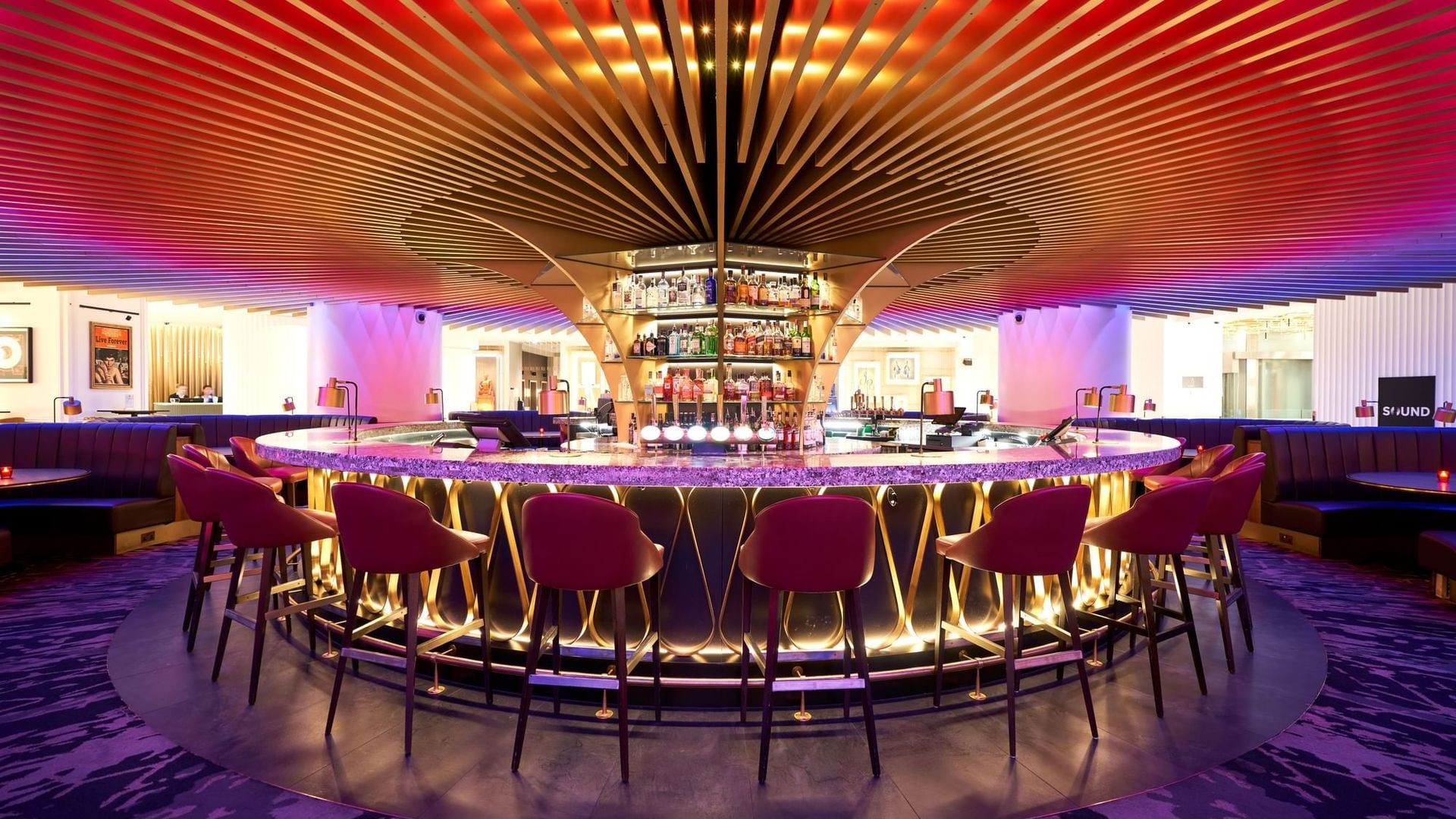 Modern circular bar with vibrant lighting and plush seating in a stylish lounge.